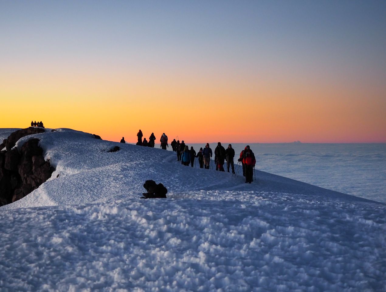 Bergsteigergruppe auf schneebedecktem Pfad im Kilimandscharo bei Sonnenaufgang – ein magischer Moment während der Besteigung Kilimandscharo.